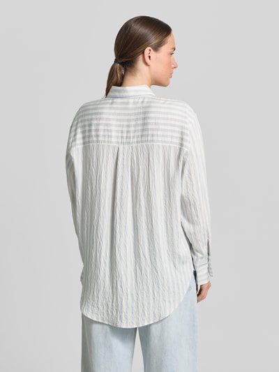 Frauenmodel trägt Relaxed Fit Bluse aus Viskose-Mix von Comma, weiß mit feinen Streifen, Hemdblusenkragen, Knopfleiste, Rückenlänge 76 cm, Ärmellänge 57 cm, Ganzkörperansicht Rückansicht.