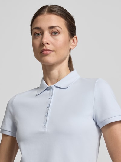 Frauenmodel trägt Slim Fit Poloshirt mit Knopfleiste von Christian Berg Woman aus Baumwoll-Elasthan-Mix in Hellblau, Nahaufnahme Oberkörper.