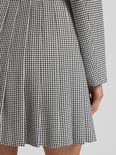 Frauenmodel trägt Mini-Faltenrock mit Vichy-Muster Modell 'RABALLI' von HUGO, Optik: Allover-Muster, gelegte Falten, Mini-Länge, Nahaufnahme Oberkörper.