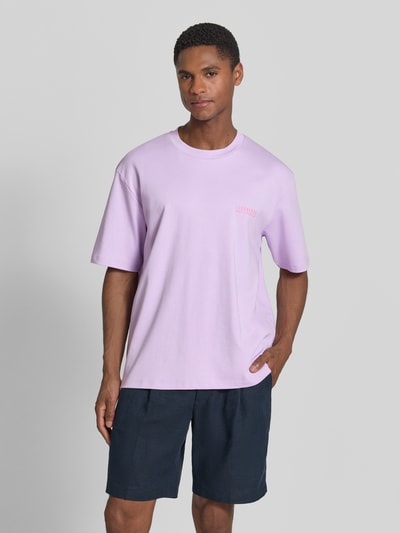 Männermodel trägt Oversized T-Shirt mit Label-Print von Lindbergh in Flieder, Reine Baumwolle, Rundhalsausschnitt, Ganzkörperansicht von vorne.