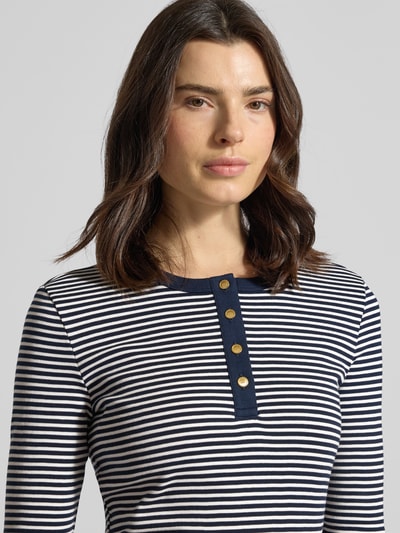 Frauenmodel trägt Slim Fit T-Shirt aus reiner Baumwolle von Tommy Hilfiger in Two-Tone-Optik, gestreift, Logo-Detail, Feinripp, Nahaufnahme Oberkörper.