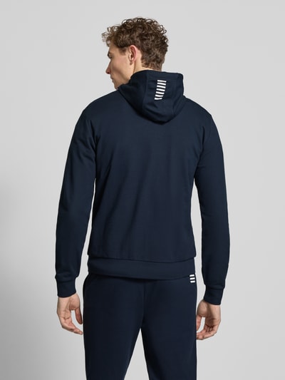 Männermodel trägt Slim Fit Sweatjacke mit Kapuze von EA7 Emporio Armani in Dunkelblau, elastischer Baumwoll-Mix, Rückenansicht.