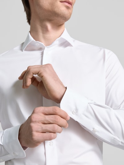 Männermodel trägt weißes 'Slim Fit Business-Hemd mit Knopfleiste' von CRUNA, Haifischkragen, Material-Mix mit Stretch, Nahaufnahme Oberkörper.