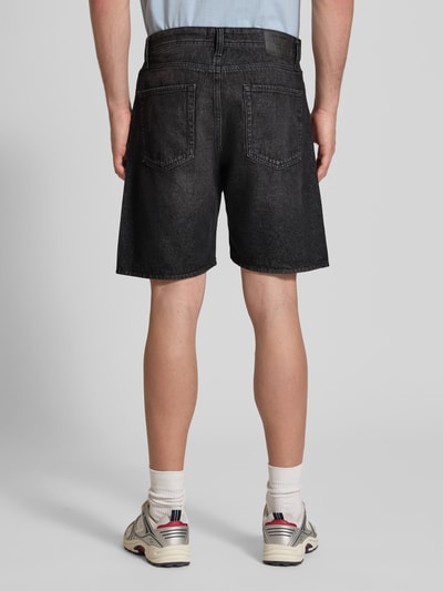 Männermodel trägt Loose Fit Jeansshorts mit Eingrifftaschen Modell 'TONY' von Jack & Jones, schwarze Used-Optik, reine Baumwolle, Ganzkörperansicht Rückansicht.