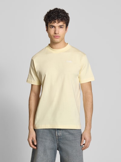 Męski model nosi jasnobeżowe T-Shirt mit Label-Stitching Modell 'ACCIANO CLASSIC' von Ellesse z bawełny, prosty krój, gładka faktura, całkowity widok z przodu.