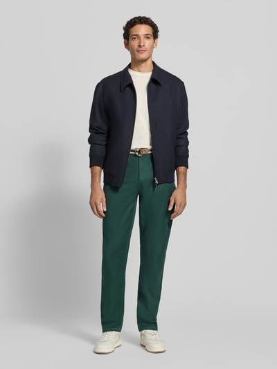 Männermodel trägt grüne Hose mit Gürtel Modell 'WARREN' von Scotch & Soda, Baumwoll-Elasthan-Mix, Regular Fit, Ganzkörperansicht von vorne.