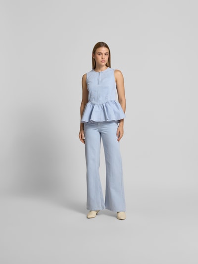 Frauenmodel trägt Straight Fit Jeans mit Logo-Patch von BAUM & PFERDGARTEN in hellem Blau, Baumwoll-Mix, 5-Pocket-Design, Ganzkörperansicht von vorne.