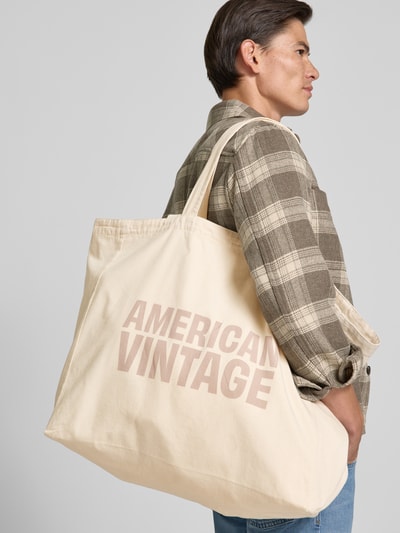 Männermodel trägt Tote Bag aus reiner Baumwolle Modell 'Lycaz' von American Vintage mit Logo-Print, Detailaufnahme schräg von hinten.