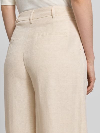 Kobiece model prezentuje Leinenhose mit angedeuteten Gesäßleistentaschen von Christian Berg Woman Selection, mieszanka lnu i wiskozy, jasny beż, zaszewki, zapięcie na haftkę i zamek błyskawiczny, szerokość w rozmiarze 36: 42 cm, długość wewnętrzna nogawki w rozmiarze 36: 71 cm, detal tylnej kieszeni z wypustką, ujęcie z tyłu.