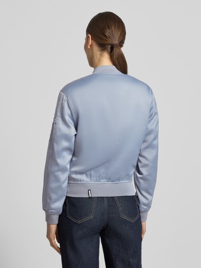 Frauenmodel trägt Regular Fit Bomberjacke mit Stehkragen Modell 'Beth' von khujo in Hellblau, glatter Stoff, Rückenansicht, Ganzkörperansicht. Elastischer Material-Mix, elastische Ärmelabschlüsse, Eingrifftaschen, Reißverschluss.