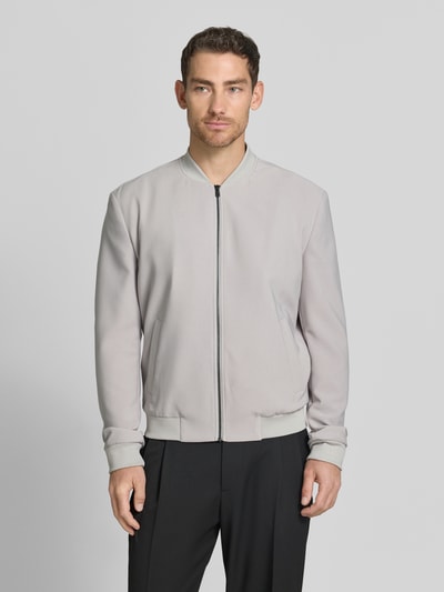 Männermodel trägt Blouson mit seitlichen Eingrifftaschen von MCNEAL aus Material-Mix mit Stretch-Anteil, Regular-Fit, Stehkragen, Reißverschluss, elastische Abschlüsse, Farbe hellgrau, glatte Textur, Ganzkörperansicht von vorne.