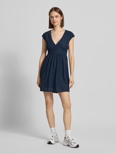 Frauenmodel trägt Kurzes Kleid mit V-Ausschnitt, Lochstickerei und großer Schleife von REVIEW, Dunkelblau, A-Linie, Material-Mix mit Stretch-Anteil, Ganzkörperansicht von vorne.