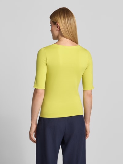 Modelka nosi T-Shirt mit Rundhalsausschnitt und 1/2-Arm von Marc Cain, Mieszanka bawełny i elastanu, krój regular fit, okrągły dekolt, rękaw o dł. 1/2, Długość tyłu w rozmiarze 36: 54 cm, gładka faktura w kolorze limonkowym i granatowym, widok całej sylwetki z tyłu.