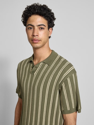 Männermodel trägt Regular Fit Strick-Poloshirt Modell 'POUL' von Redefined Rebel aus Baumwoll-Mix mit Knopfleiste und Streifenmuster, Nahaufnahme Oberkörper.