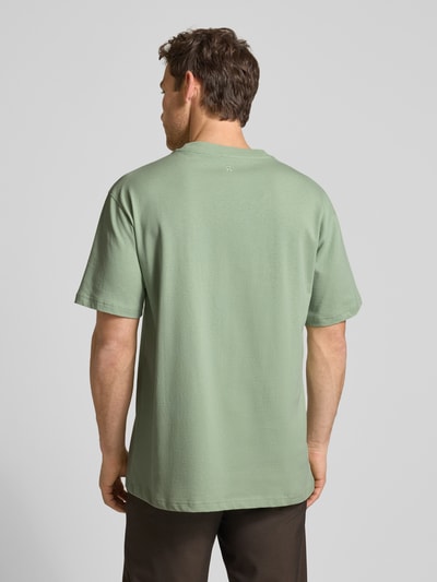 Männermodel trägt Relaxed Fit T-Shirt aus reiner Baumwolle Modell 'MAARKOS HEAVY WEIGHT' von Armedangels in hellem Grün, Unifarben, Jerseytextur, Logo-Stitching, Rundhals, kurzarm, Ganzkörperansicht Rückansicht.