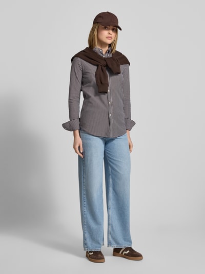 Frauenmodel trägt Hemdbluse mit Knopfleiste von Polo Ralph Lauren aus reiner Baumwolle im Regular-Fit, braun-weiß gestreift mit Button-Down-Kragen, Label-Stitching, kombiniert zu weiter Jeans, Ganzkörperansicht von vorne.