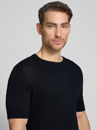 Männermodel trägt Regular Fit T-Shirt aus reiner Baumwolle Modell 'ADRIAN-TC' von Strellson in Strickoptik mit Zopfmuster, Nahaufnahme Oberkörper.