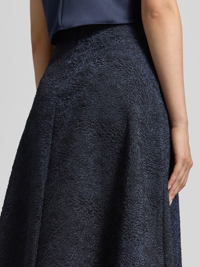 Vrouwenmodel draagt midirok met structuurpatroon van Rinascimento in donkerblauw met elastische materiaalmix, a-lijn, naadritssluiting, bandwijdte maat S 35 cm, totale lengte maat S 90 cm, detailopname heup.