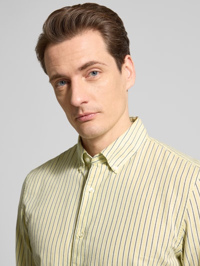 Männermodel trägt Slim Fit Freizeithemd aus reiner Baumwolle von MCNEAL in Gelb mit blauen Streifen, Button-Down-Kragen, Nahaufnahme Oberkörper.