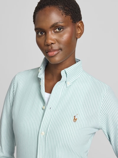 Frauenmodel trägt Regular Fit Hemdbluse aus reiner Baumwolle von Polo Ralph Lauren in Hellgrün mit weißen Streifen, Nahaufnahme Oberkörper. Damen Hemdbluse von Polo Ralph Lauren.