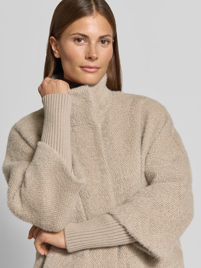 Kobiece modelka nosi Relaxed Fit płaszcz z fakturowanym wzorem od COMMA, stójka, wpuszczane kieszenie, elastyczne zakończenia rękawów, długość tyłu w rozmiarze 36: 98 cm, szerokość ramion w rozmiarze 36: 40 cm, szerokość klatki piersiowej w rozmiarze 36: 57 cm, długość rękawów w rozmiarze 36: 49 cm, beżowy odcień, miękka tekstura, zbliżenie na górną część ciała, frontalny widok.