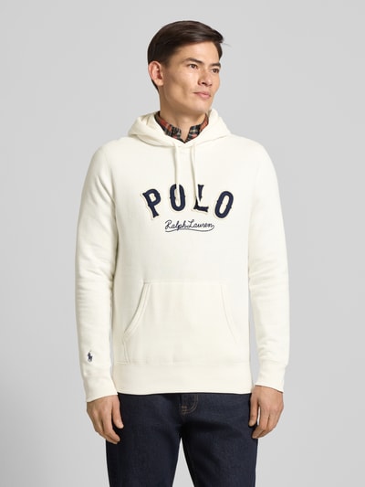 Männermodel trägt Hoodie mit Label-Stitching und Känguru-Tasche von Polo Ralph Lauren, cremefarben, Regular Fit, Ganzkörperansicht von vorne.