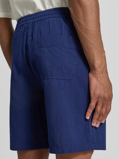Männermodel trägt Regular Fit Shorts aus reiner Baumwolle Modell 'STUART' von SELECTED HOMME, Optik: Unifarben, Materialverarbeitung: Seersucker, seitliche Eingrifftaschen, Gesäßtaschen, Elastisch, Ganzkörperansicht Rückansicht.