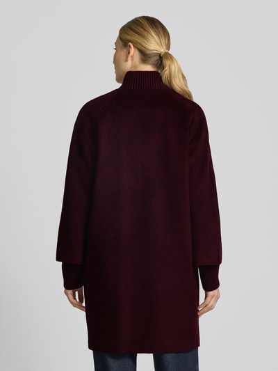 Frauenmodel trägt Mantel aus Woll-Mix mit gestricktem Stehkragen von COMMA in Weinrot, gerade Form, strukturierte Textur, Ganzkörperansicht Rückansicht. Woll-Mix mit Viskose, Reiß- und Druckknopfverschluss, seitliche Eingrifftaschen, gestrickte Ärmelabschlüsse, Rückenlänge 92 cm, Schulterbreite 40 cm, Brustweite 60 cm, Ärmellänge 63 cm.