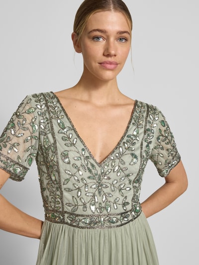 Frauenmodel trägt Knielanges Kleid mit floralem Pailettenbesatz von LACE & BEADS in Hellgrün, taillierte Passform, Mesh, V-Ausschnitt, Kurzarm, Nahaufnahme Oberkörper.