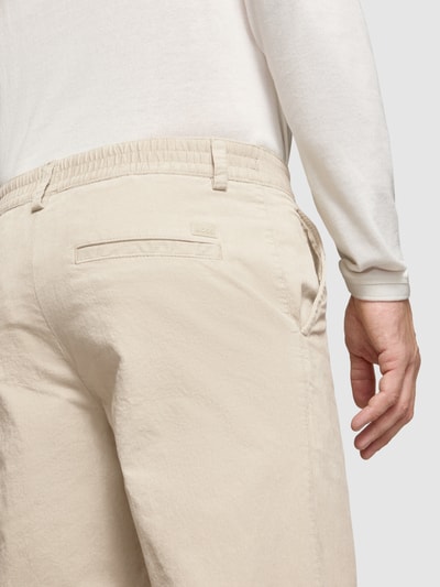 Mężczyzna nosi chinosy Straight Fit Chino aus Baumwoll-Mix model 'Chino_Keyes_DS' od BOSS Orange, jasny beż, gładka faktura, detal z tyłu, KI-modifiziertes Bild