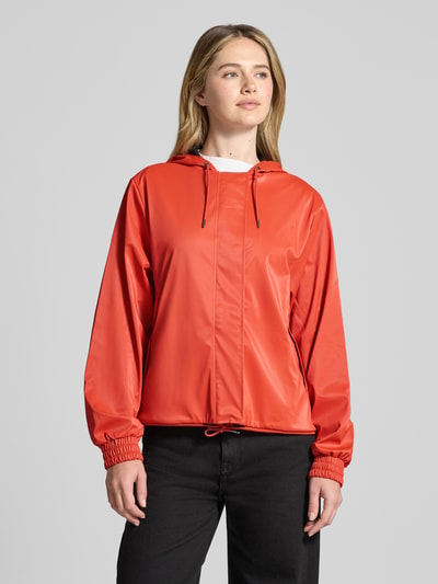 Modelka kobieca nosi Jacke mit Abdeckleiste od RAINS w kolorze czerwonym, krój regular fit, kaptur z troczkiem, suwak zakryty listwą, troczek w dole, elastyczne mankiety, długość tyłu w rozmiarze S: 58 cm, szerokość ramion w rozmiarze S: 43 cm, szerokość w klatce piersiowej w rozmiarze S: 55 cm, długość rękawa w rozmiarze S: 63 cm, gładka tekstura, widok całej sylwetki z przodu