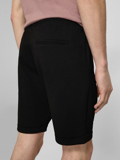 Männermodel trägt Shorts mit elastischem Bund und Gesäßtasche von MCNEAL in Schwarz, Material-Mix mit Viskose-Anteil, Regular-Fit, Ganzkörperansicht Rückansicht.