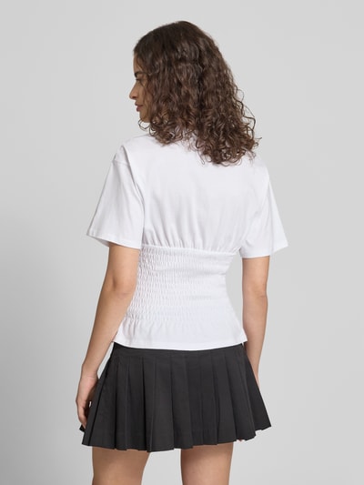 Modelka nosi tailliertes T-Shirt mit Rundhalsausschnitt Modell 'EVELYN' von JJXX, czysta bawełna, krój slim fit, detale smock, długość tyłu w rozm. S: 53 cm, widok całej sylwetki z tyłu.