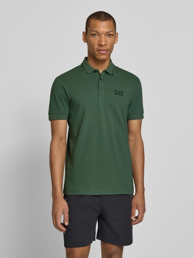 Męski model nosi Regular Fit Poloshirt mit Logo-Print od EA7 Emporio Armani, zielony, krój regular fit, bawełna elastyczna, przód, ujęcie całej sylwetki.