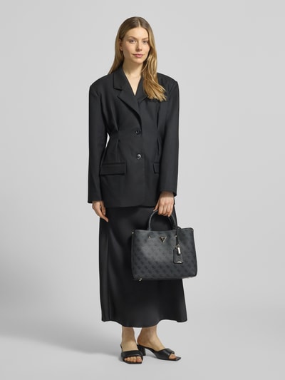Frauenmodel trägt Handtasche mit Label-Applikation Modell 'MERIDIAN II' von Guess mit Logo-Muster, Hauptfach mit Reißverschluss, Tragehenkel und Schulterriemen, Schwarz mit dezenter Struktur, Maße ca. 31x24x11 cm, Länge Schulterriemen 105 cm, Ganzkörperansicht von vorne.
