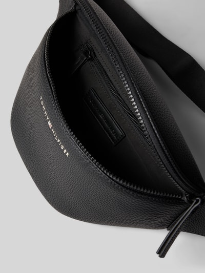 Produktfoto, Bauchtasche mit Strukturmuster von Tommy Hilfiger in Schwarz, robustes Material, Hauptfach mit Reißverschluss, Label-Schriftzug, Logo-Details, Reißverschlussfach innen, verstellbarer Schulterriemen mit Klickverschluss, Maße: Breite 36 cm, Länge 15 cm, Tiefe 5 cm, Schulterriemenlänge 90 cm.