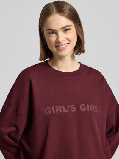 Frauenmodel trägt Sweatshirt mit Statement-Print und überschnittenen Schultern von OH APRIL in Bordeaux, Reine Baumwolle, Regular-Fit, Gerippter Rundhalsausschnitt, Gerippte-Abschlüsse, Nahaufnahme Oberkörper.
