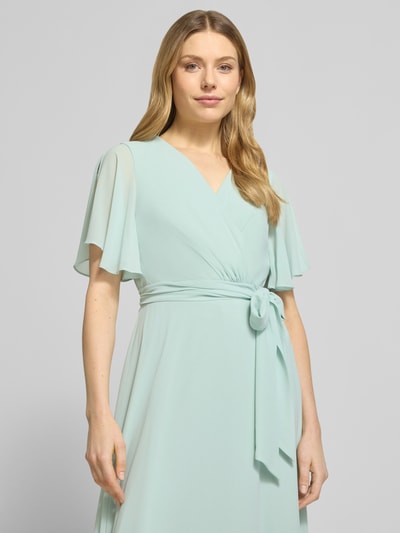 Vrouwenmodel draagt Regular Fit Abendkleid mit V-Ausschnitt van Christian Berg Cocktail in lichtgroen, taillering, korte mouwen, afneembare stoffen riem, ondoorzichtige onderrok, bovenlichaam close-up vooraanzicht.