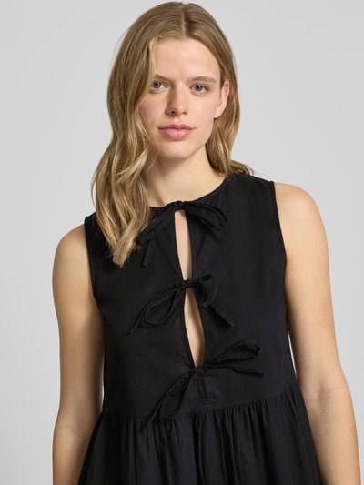 Frauenmodel trägt Ausgestelltes Blusenkleid aus reiner Baumwolle Modell 'JOLLY' von Pieces, uni schwarz, ärmellos, Rundhals, Nahaufnahme Oberkörper.