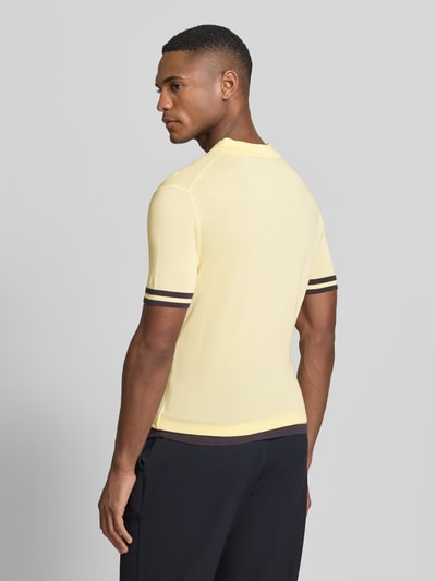 Mężczyznamodel nosi Slim Fit Poloshirt aus Lyocell-Seide-Mix von Guess, żółty z kontrastowymi paskami, krój slim fit, widok tyłu całej sylwetki.