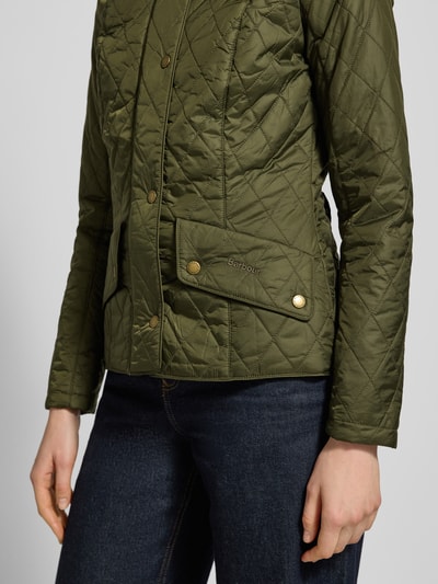 Frauenmodel trägt Regular Fit Steppjacke mit Stehkragen Modell 'FLYWEIGHT' von Barbour in Olivgrün, Steppoptik, Nahaufnahme Oberkörper.