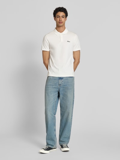 Männermodel trägt Slim Fit Poloshirt mit Label-Stitching von REVIEW in Weiß, reine Baumwolle, Knopfleiste, Ganzkörperansicht von vorne.