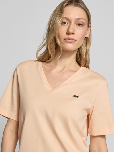 Frauenmodel trägt Relaxed Fit T-Shirt aus reiner Baumwolle von Lacoste in Apricot, unifarben mit Logo-Stitching, Nahaufnahme Oberkörper.