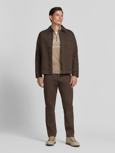 Männermodel trägt Wollpullover mit Label-Patch Modell 'Liaset' von Dale of Norway in Beige, kombiniert mit brauer Jacke und Hose, Gerade Schnitt, Troyer-Kragen, Reine Wolle, Ganzkörperansicht von vorne.