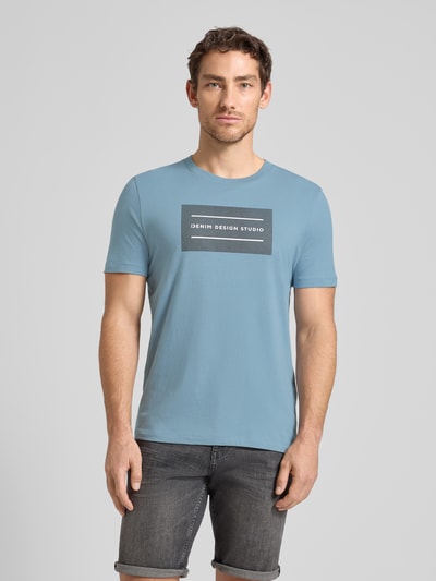 Männermodel trägt Regular Fit T-Shirt aus reiner Baumwolle von Tom Tailor Denim, unifarben, kurzer Ärmel, Rundhals, Label-Schriftzug, Ganzkörperansicht von vorne.