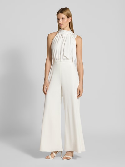 Vrouwenmodel draagt Jumpsuit mit Schleifen-Applikation van SWING in wit, getailleerd model met wijde benen, halter en cut-out op de rug, geheel zichtbaar, vooraanzicht.