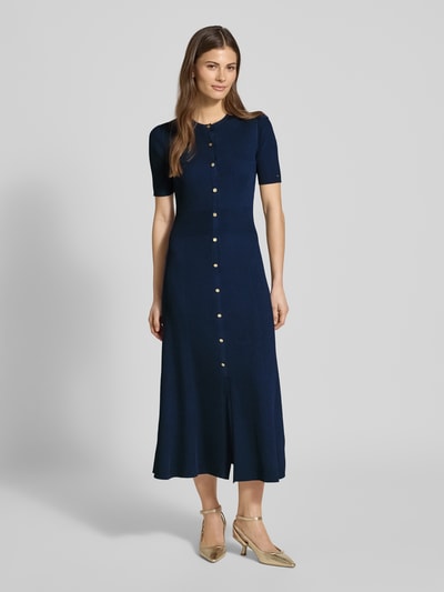 Frauenmodel trägt eng anliegendes Freizeitkleid aus Viskose-Mix von Tommy Hilfiger, Optik: Unifarben, Passform, Midi-Länge, Rundhals, Logo-Detail, Zierknöpfe, Knopfleiste, Kurzarm, Ganzkörperansicht von vorne.