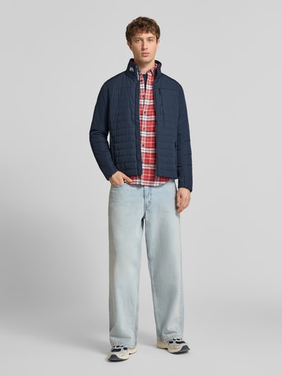 Männermodel trägt Regular Fit Jacke mit Stehkragen von Helly Hansen in Dunkelblau, Logo-Print, Eingrifftaschen mit Reißverschluss, Ganzkörperansicht von vorne. Rückenlänge bei Größe M: 70 cm, Schulterbreite: 46 cm, Brustweite: 54 cm, Ärmellänge: 69 cm.
