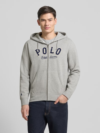Männermodel trägt Sweatjacke mit Label-Stitching und Känguru-Tasche von Polo Ralph Lauren, hellgrau, Baumwoll-Mix, Regular-Fit, Ganzkörperansicht von vorne.