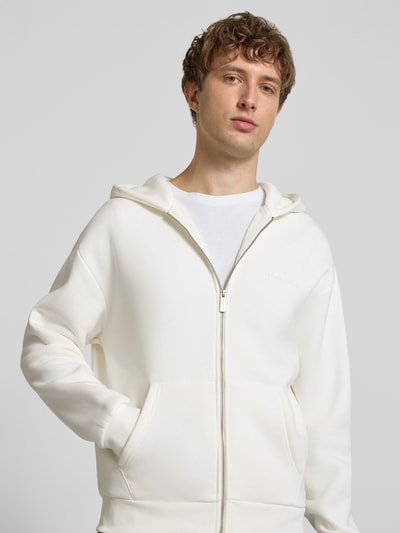 Männermodel trägt Regular Fit Sweatjacke mit Känguru-Tasche von REVIEW in Creme, Baumwoll-Mix, Reißverschluss, Kapuze, Nahaufnahme Oberkörper.